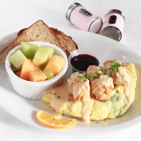 Shrimp omelet with sauce, fruit cup, toast, and a side of jelly on a white plate.