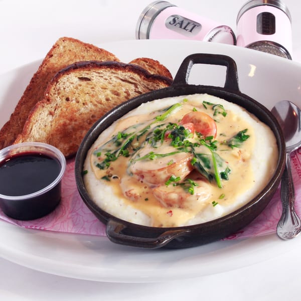 Shrimp and grits with spinach and tomatoes in a skillet, served with toast and jam.